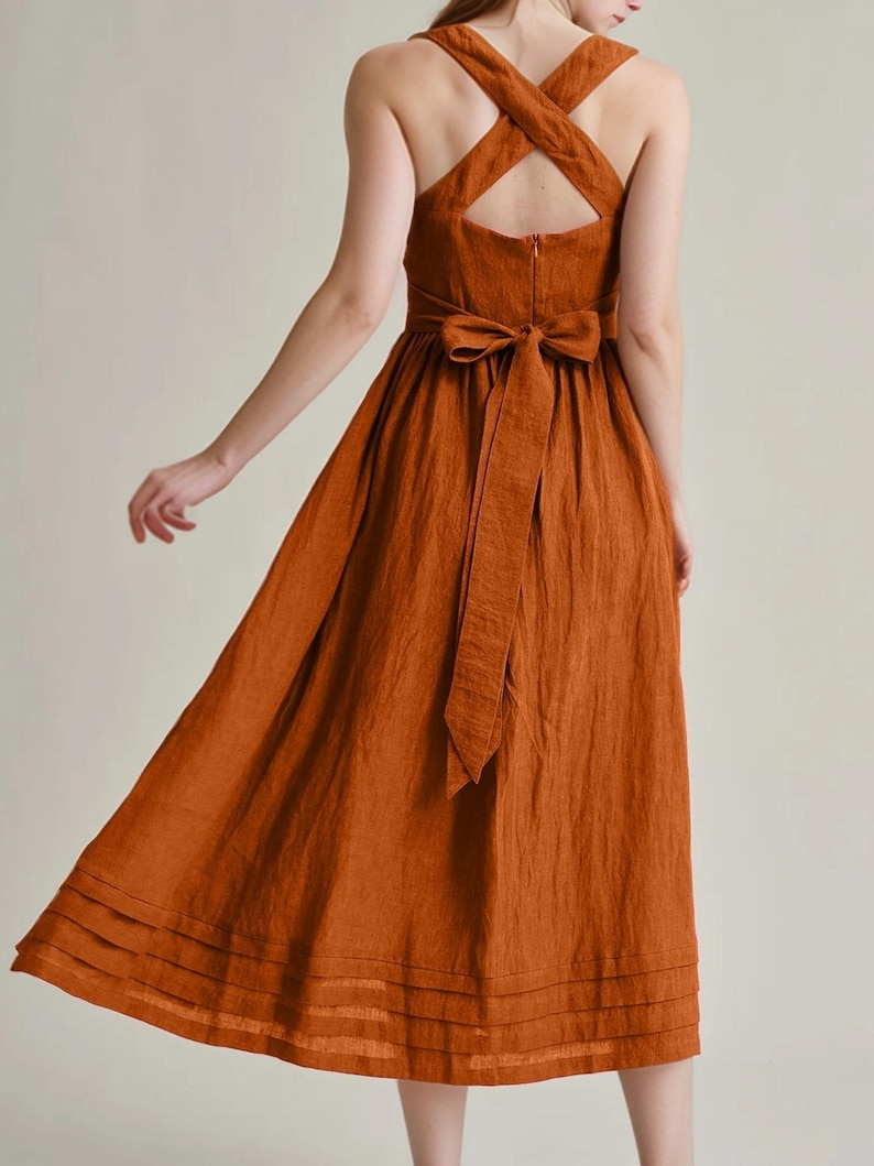 a woman in an orange dress with a cross back