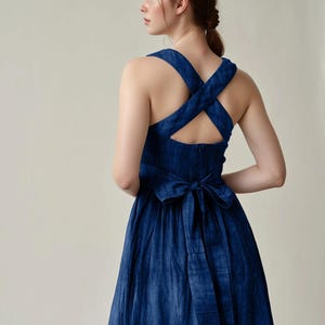 a woman wearing a blue dress with a cross back