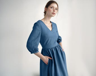 May include: A blue linen dress with a v-neckline and 3/4 sleeves. The dress has a fitted bodice and a flowing skirt.