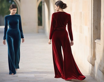 May include: Two women wearing long-sleeved velvet jumpsuits. One jumpsuit is teal blue and the other is burgundy red.