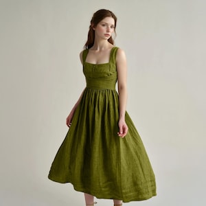 a woman in a green dress standing in front of a white wall