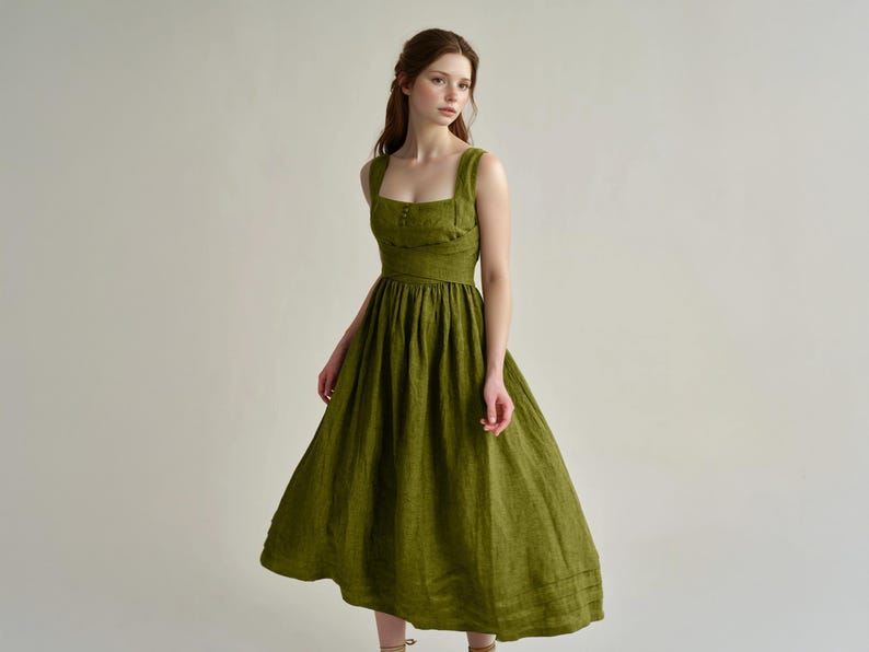 a woman in a green dress standing in front of a white wall
