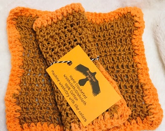 May include: Two hand-crocheted washcloths/dishcloths. The washcloths are brown with orange borders. A tag attached to the washcloths reads "Hand Crocheted Washcloth/Dishcloth 100% Cotton Machine wash/Dry with like colors."