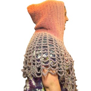 May include: A crocheted hooded scarf in shades of pink and purple. The hood is a solid pink color, while the scarf is a lighter purple with a lacy pattern.