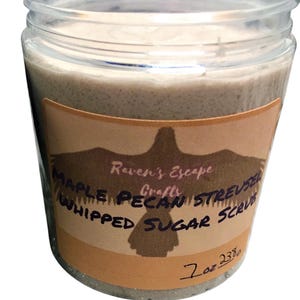 Könnte beinhalten: Ein braunes Glasgefäß mit einem beigefarbenen Etikett, auf dem "Raven's Escape Crafts Maple Pecan Streusel Whipped Sugar Scrub" und "7 oz 233g" steht.
