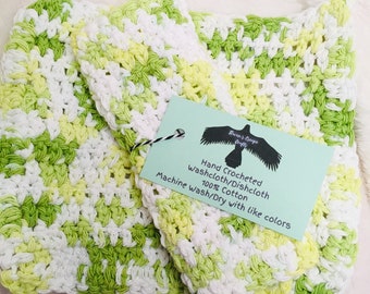 Pode incluir: Dois panos de cozinha de crochê em verde, branco e amarelo. Os panos de cozinha são feitos de 100% algodão e são laváveis na máquina. A etiqueta diz "Hand Crocheted Washcloth/Dishcloth 100% Cotton Machine Wash/Dry with like colors".