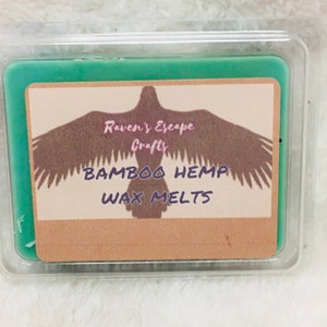 Puede incluir: Un derretimiento de cera verde con una etiqueta marrón que presenta una silueta de un pájaro con el texto "Raven's Escape Crafts, Bamboo Hemp Wax Melts".