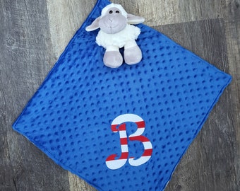 May include: A blue baby blanket with a white sheep plush toy and a red and white letter B embroidered on it.