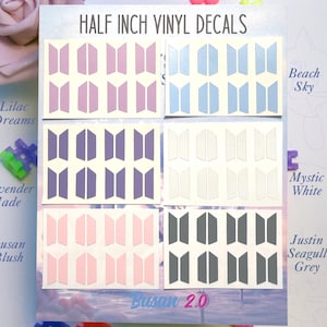 May include: A display of half-inch vinyl decals in various colors, including lavender, pink, blue, and gray. The decals feature a geometric design and are labeled with color names such as "Lilac Dreams" and "Beach Sky". The text "HALF INCH VINYL DECALS" is visible.