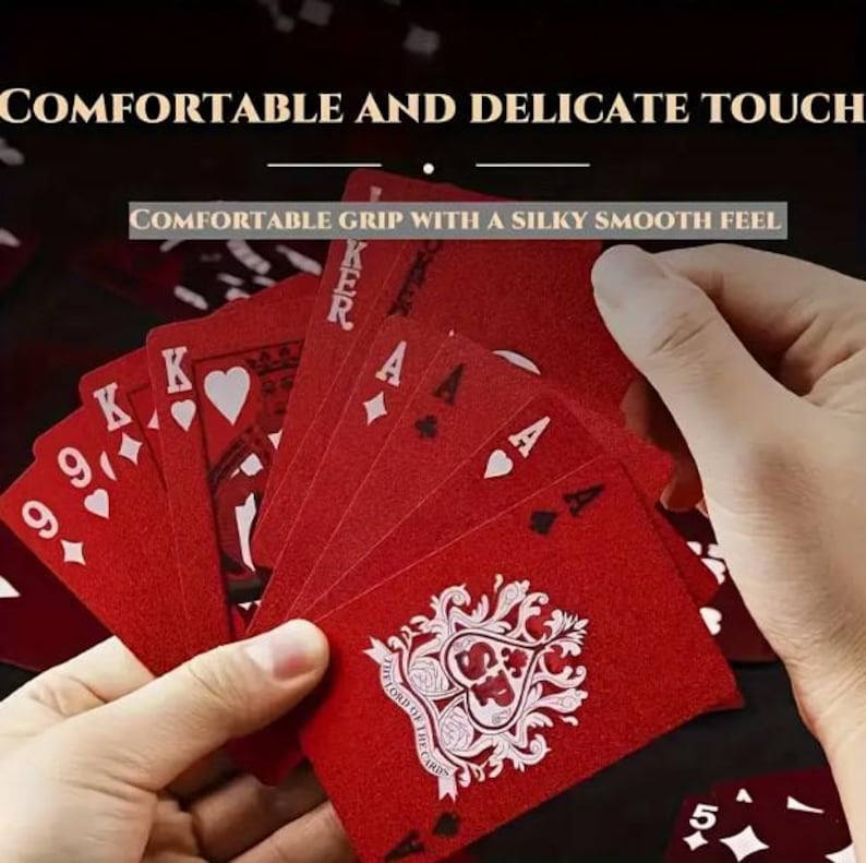May include: A hand holding a fanned deck of red playing cards. The cards feature white suits, numbers, and face cards. The text "COMFORTABLE AND DELICATE TOUCH" and "COMFORTABLE GRIP WITH A SILKY SMOOTH FEEL" are visible.