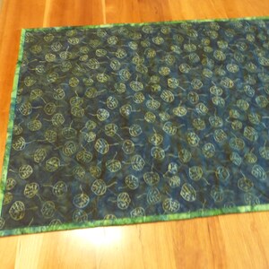 May include: A rectangular fabric table runner featuring a dark blue and black batik-style background with a repeating pattern of light green and yellow outlined leaves. The runner is finished with a bright green mottled fabric border.