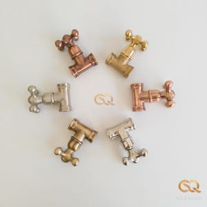 May include: Six antique-style water faucet handles in different finishes: copper, brass, nickel, and chrome. The handles are arranged in a circle on a white background.
