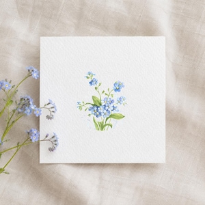 Könnte beinhalten: Eine quadratische weiße Karte mit einem Aquarellgemälde eines Straußes blauer Vergissmeinnicht-Blumen und grünen Blättern. Ein Zweig derselben Blumen befindet sich links. Der Hintergrund ist ein neutraler Leinenstoff.