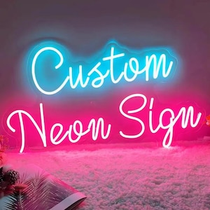 May include: A neon sign with the words "Custom" and "Neon Sign" in a cursive font. The top sign is blue, and the bottom sign is pink. The sign is on a fluffy pink surface.
