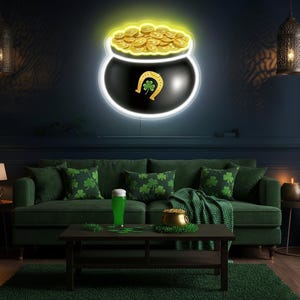 Könnte beinhalten: Ein Wohnzimmer im St. Patrick's Day-Stil mit einem grünen Sofa, Kissen mit Kleeblattmustern und einem Couchtisch. Über dem Sofa befindet sich ein Neonschild mit einem Goldtopf mit Hufeisen und Kleeblatt. Ein Glas grünes Bier und ein Goldtopf stehen auf dem Tisch.