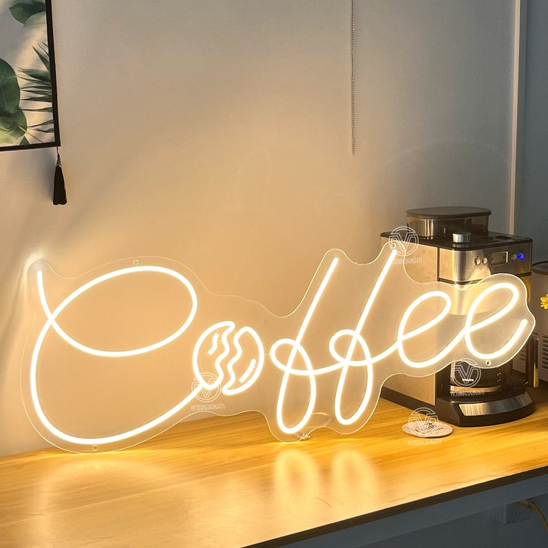 May include: White neon sign with the word "Coffee" in a cursive font. The sign includes a stylised coffee bean graphic.