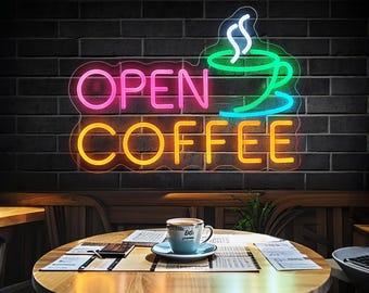 May include: Neon sign with the words "OPEN COFFEE" in pink, yellow, and green. A stylized coffee cup with steam is above the words. The sign is on a brick wall.