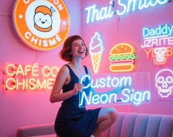 May include: A woman holds a clear neon sign that reads "Custom Neon Sign" in blue. The background features various neon signs, including "Thai Smile," a skull, and food-related designs. The room is lit with pink and blue neon lights.