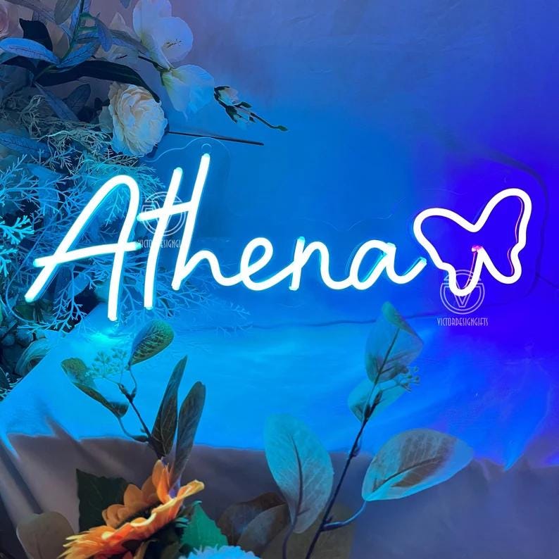 May include: A neon sign in the shape of the name "Athena" in white script, with a butterfly outline. The sign is set against a gradient blue background, with floral accents in the foreground.