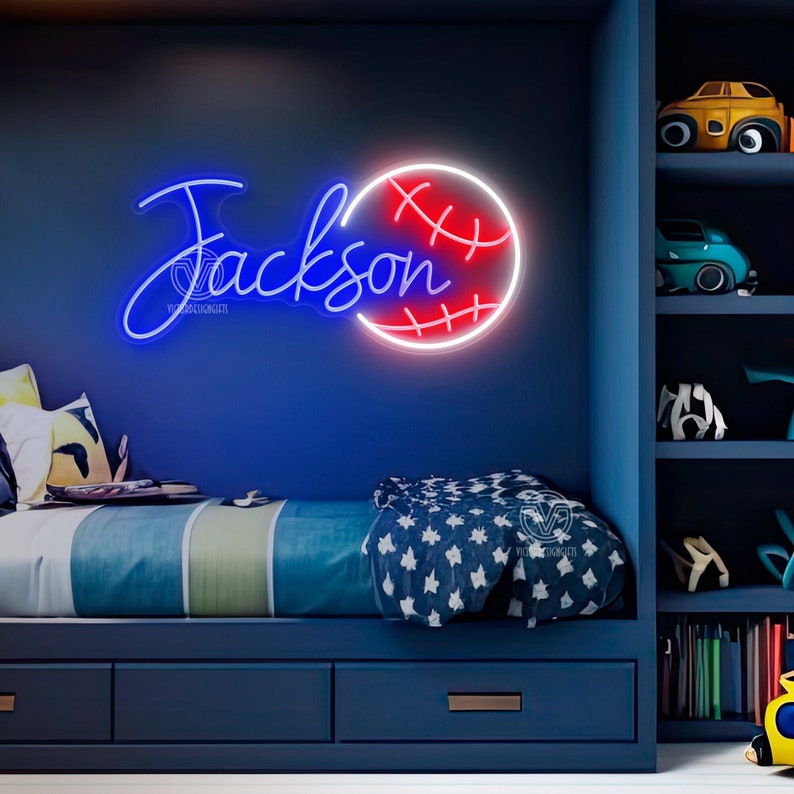 May include: A blue and red neon sign with the name "Jackson" and a baseball. The sign is hanging on a blue wall in a bedroom with a bed and a bookshelf.