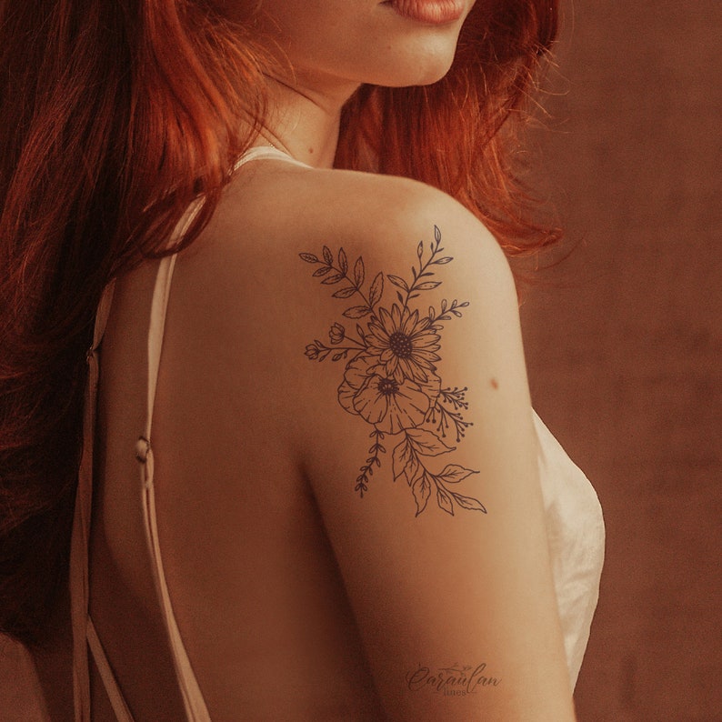 May include: A black line art tattoo design of a floral bouquet with leaves and flowers on a person's shoulder.