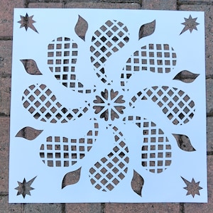 Puede incluir: Plantilla blanca con un diseño decorativo que presenta una flor en el centro rodeada de ocho hojas estilizadas con un patrón de cuadrícula. La plantilla es perfecta para crear un diseño único e intrincado en paredes, muebles u otras superficies.