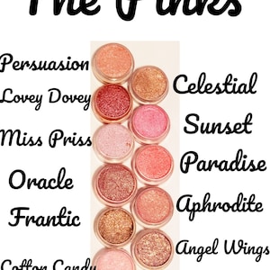 May include: A collection of 12 small round jars of shimmery pink, gold, and peach eyeshadows. The jars are arranged in two rows of six. Each jar has a label with a different name, such as "Persuasion", "Lovey Dovey", "Miss Priss", "Oracle", "Frantic", "Cotton Candy", "Frolic", "Ms Monroe", "Celestial", "Sunset", "Paradise", "Aphrodite", "Angel Wings", "Psycho", "Let Go And", and "Let Goth".