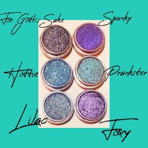 Può includere: Sei piccoli barattoli rotondi di ombretto glitterato. I barattoli sono etichettati con i nomi "For Goth's Sake", "Spunky", "Hottie", "Prankster", "Lilac" e "Foxy".