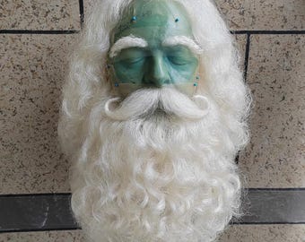 May include: A white wig with a long, curly beard and moustache. The wig is made of synthetic hair and is designed to look like a Father Christmas beard.