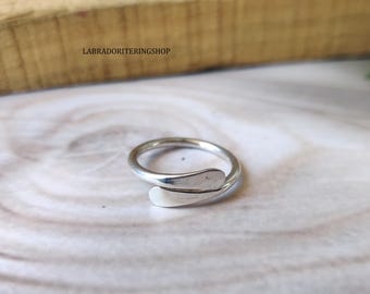 May include: A silver ring with a unique design, featuring a curved band that wraps around the finger. The ring is simple and elegant, making it a perfect accessory for any occasion.