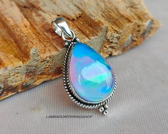 May include: A teardrop-shaped pendant featuring a blue and iridescent opal gemstone set in a silver bezel. The pendant has a silver bail and a beaded edge.