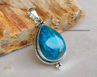 May include: A teardrop-shaped pendant featuring a blue and green gemstone set in a silver frame. The pendant has a silver bail for attaching to a chain.