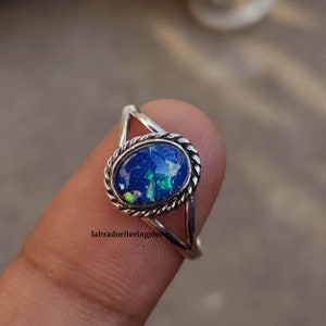 May include: A silver ring with a blue opal gemstone set in a twisted band.