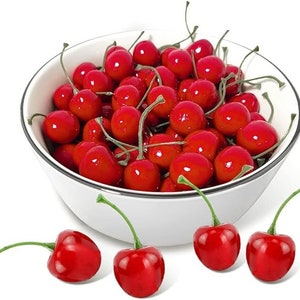 May include: A white bowl filled with bright red cherries with green stems. Several cherries are scattered around the bowl. The cherries have a glossy finish, suggesting they are fresh or artificial. The bowl has a black trim.