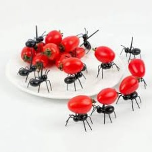 May include: Black plastic ants carrying red cherry tomatoes on a white plate.  These novelty food picks are perfect for adding a fun touch to your next party or gathering.