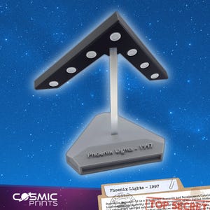 May include: A grey and black Phoenix Lights - 1997 lamp with a triangular top and base, supported by a silver pole. The top has six white lights. The Cosmic Prints logo is in the lower left.