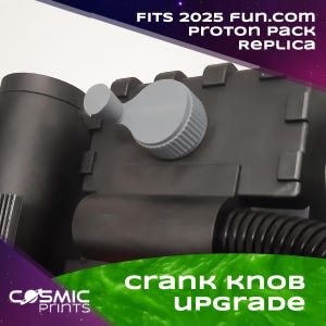 Peut inclure: Gros plan d'une réplique de Proton Pack noire avec une mise à niveau du bouton de manivelle grise. Le texte "FITS 2025 FUN.COM PROTON PACK REPLICA" est en haut. Le texte "CRANK KNOB UPGRADE" est en bas. Le logo Cosmic Prints est en bas à gauche.