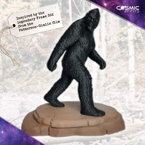 May include: A black Bigfoot figurine, inspired by Frame 352 from the Patterson-Gimlin film, stands on a brown, rock-like base. The figurine has a textured, hairy appearance. The tag reads "Inspired by the legendary Frame 352 from the Patterson-Gimlin film."
