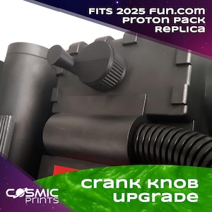 Peut inclure: Gros plan d'une réplique noire de Proton Pack avec une mise à niveau du bouton de manivelle. L'image présente le texte "FITS 2025 FUN.com PROTON PACK REPLICA" et "CRANK KNOB UPGRADE". Le logo Cosmic Prints est visible en bas à gauche.
