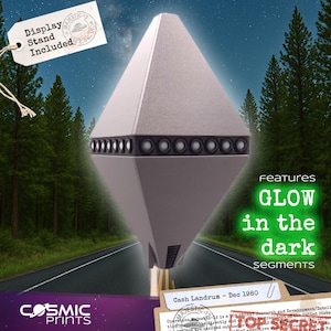 May include: A silver-colored, diamond-shaped object with a row of black speakers. The text "Display Stand Included" is on a tag. The image also features the text "GLOW in the dark segments" and "Cosmic Prints".