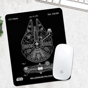 May include: A black rectangular mouse mat featuring a white technical line drawing of the Millennium Falcon. The print includes the text U.S. Patent, Apr. 19, 1979, Des. 228,688, Fig. 1, Fig. 2, STAR WARS, and MILLENNIUM FALCON. A white computer mouse sits on top.