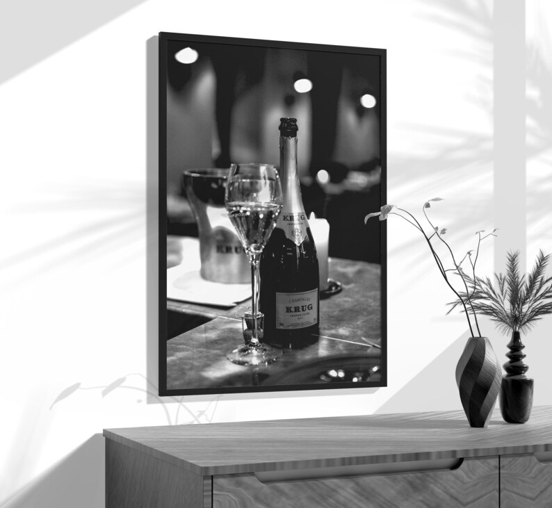 a black and white photo of a bottle of wine and two glasses