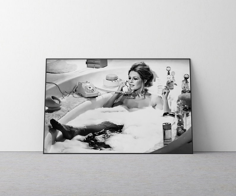 Puede incluir: Impresi&oacute;n enmarcada en blanco y negro de una mujer en una ba&ntilde;era llena de burbujas, usando un tel&eacute;fono vintage. La imagen incluye un tel&eacute;fono retro, productos de ba&ntilde;o y una alfombra de ba&ntilde;o esponjosa.