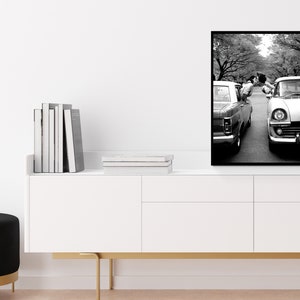 a black and white photo of a couple standing next to a car
