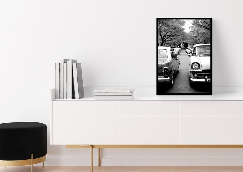 a black and white photo of a couple standing next to a car
