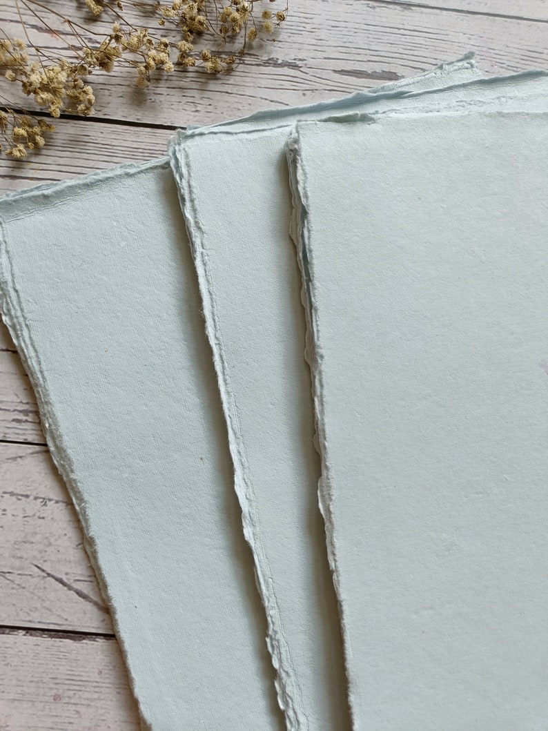 May include: Three sheets of light blue handmade paper with deckled edges.
