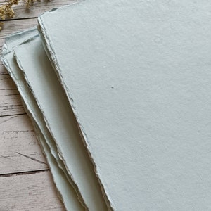 May include: Stack of light blue handmade paper with deckled edges.