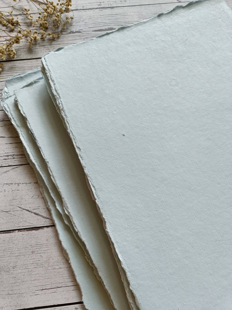 May include: Stack of light blue handmade paper with deckled edges.