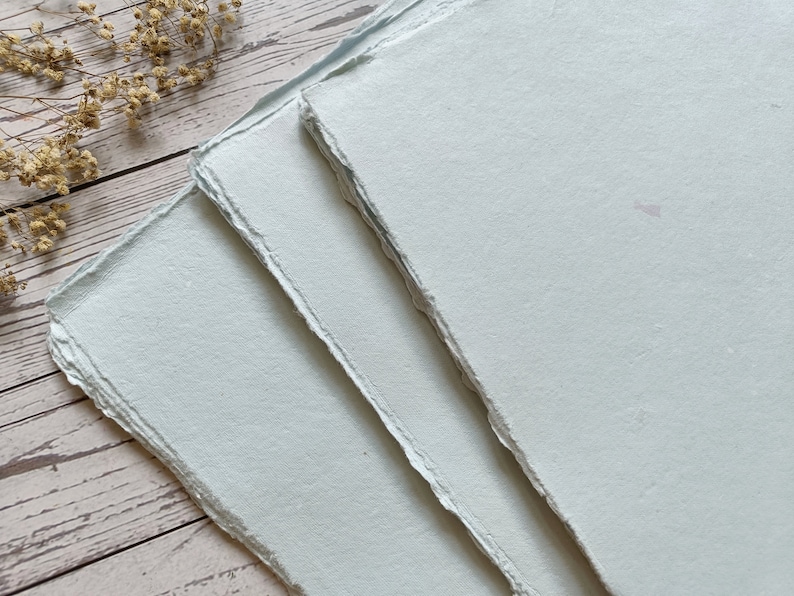 May include: Three sheets of light blue handmade paper with deckled edges.