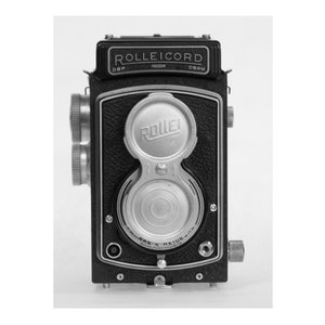 May include: A black and silver Rolleicord twin-lens reflex camera with the text "ROLLEICORD" and "ROLLEI" on the front.